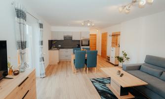 A modern apartment with an open kitchen and a dining area. The space is bright and cozily furnished.
