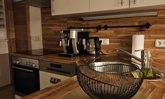 A modern kitchen with wooden shelves and an elegant countertop. In the foreground, there is a decorative bowl on a round placemat.