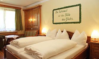 A cozy bedroom with two beds and elegant wood paneling. On the wall hangs a quote that addresses happiness.