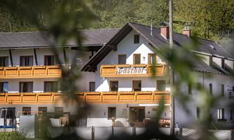 A guesthouse with a modern, bright building and wooden balconies. The surroundings are green and inviting.