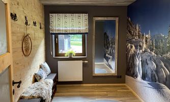 A modern room with wood paneling and a large mirror.  
On the wall, there is a winter landscape painting that creates a cozy atmosphere.