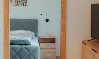 A cozy bedroom with a upholstered bed and a nightstand. The room is decorated in soft colors and has a pleasant atmosphere.