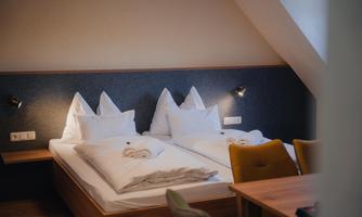A cozy room with two beds and white pillows. The walls are light and the space feels inviting and modern.