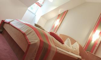 A cozy bedroom with a large bed and modern, colorful accents. The room has plenty of light and an inviting atmosphere.