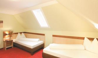 A cozy room with two single beds and a window. The walls are painted in a soft shade of yellow and the floor is red.