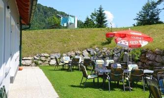 An inviting garden with tables and chairs outdoors. In the background, laundry is hanging and there is a parasol.
