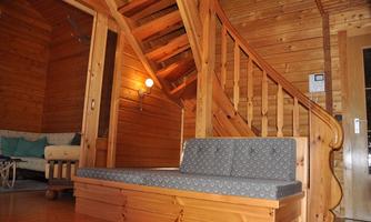 A bright wood interior with a cozy bench and a wooden staircase. In the background, a sofa is visible, creating an inviting atmosphere.
