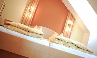 A cozy bedroom with a large bed and soft pillows. The walls are designed in warm colors and the lighting creates a pleasant atmosphere.