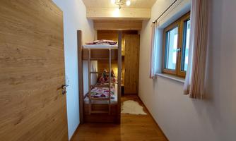 A cozy room with a bunk bed and wooden paneling. Windows provide plenty of daylight.