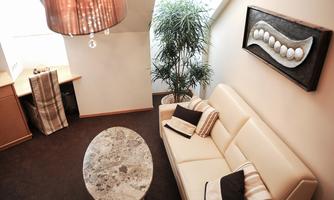 A modern living room with a white sofa and a round coffee table. A plant and a wall painting complement the cozy atmosphere.