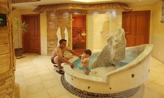 A relaxing spa with a small jacuzzi. Father and child enjoy their time together in a wood-paneled room.