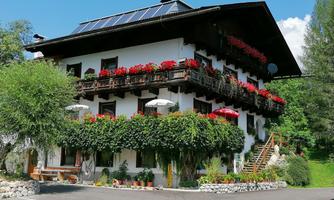 A charming multi-story building with blooming balconies. Surrounded by greenery and a clear blue sky.