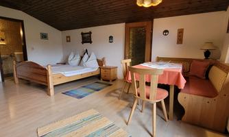 A cozy room with a bed, a table, and chairs. The decor is simple and inviting.