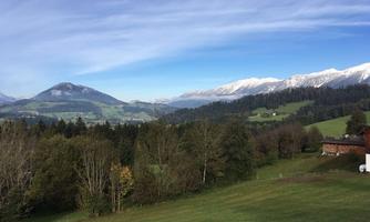 A picturesque landscape with snow-covered mountains and green meadows. The clear air and blue sky create a relaxed atmosphere.