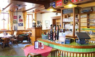 An inviting restaurant with wooden interior and a bar. Tables are set and the walls are decorated with various signs.