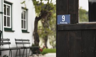 A garden gate with the number 9 and a view of the quiet courtyard. In the background, some chairs and a tree are visible.