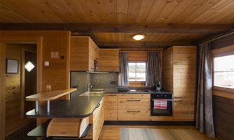 A cozy kitchen unit made of wood with modern appliances. Large windows provide plenty of daylight in an inviting atmosphere.
