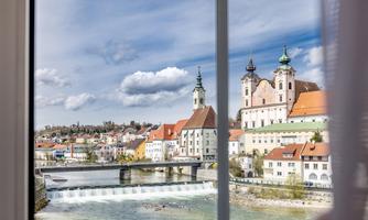 A beautiful city view with church towers and a river. The image shows picturesque architecture under a cloudy sky.