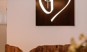 A modern sign with a heart logo on a white wall. Below, a wooden paneling is visible.