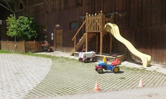 A play area with a slide and a playhouse. Colorful toys and small barriers are on the ground.