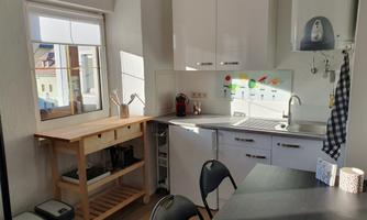 A modern kitchen with bright walls and plenty of natural light. There is a table, chairs, and a kitchenette with several appliances.