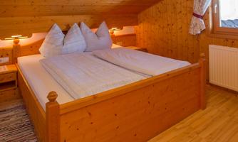 A cozy bedroom with a wooden bed and soft pillows. The warm wood tones create an inviting atmosphere.
