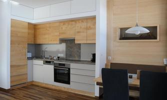 Modern kitchen with wooden cabinets and an elegant countertop. A table with chairs is visible in the background.