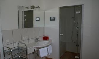 A modern bathroom with a shower cabin and a sink. Bright tiles and a clear design create a friendly atmosphere.