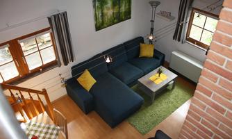 A modern living room with a blue couch and a table. Large windows provide plenty of light and a cozy atmosphere.
