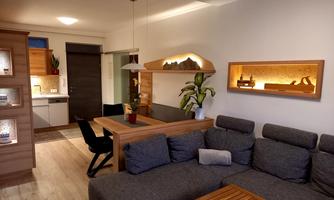 A modern living room with a gray couch and a wooden coffee table. In the background, there is an open kitchen and a quiet dining area.