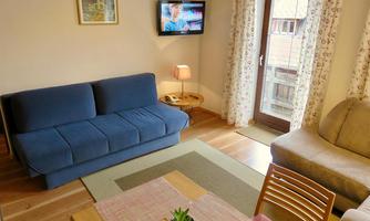 Cozy living room with a blue sofa and a beige armchair. A table with a tablecloth and a small plant complements the decor.