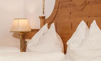 A cozy bedroom with a wooden headboard and white pillows. The soft lighting creates a warm atmosphere.