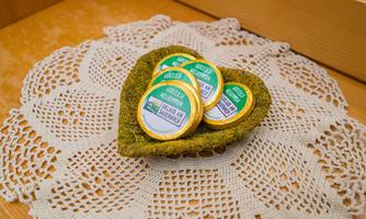 A heart-shaped bowl made of woven material contains several small slices of cheese. They are arranged on a white, crocheted placemat.
