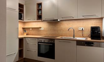 A modern kitchen with bright cabinets and wooden details. The space is well-lit and equipped with kitchen appliances.