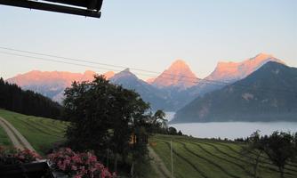 A picturesque mountain landscape with high peaks and gentle hills in the foreground. In the morning mood, the mountains shine in warm colors.