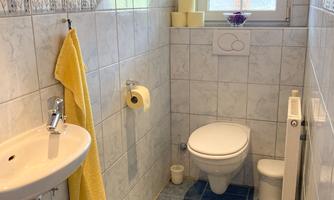 A modern bathroom with bright tiles. It features a sink, a toilet, and a window for natural light.