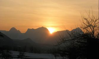 An impressive mountain landscape at sunset. The mountains are silhouetted as the sun rises on the horizon.
