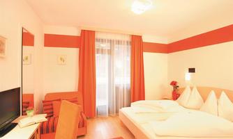 A bright room with a double bed and a small sofa.  
Large windows with curtains let in a lot of light and create a pleasant atmosphere.