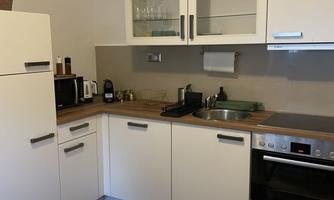 A modern kitchen with white cabinets and a wooden countertop. The table is set with dishes and glasses.