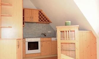 A modern kitchen with wooden cabinets and a practical layout. In the corner, there is a small table and a sink.