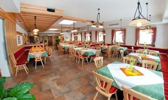 An inviting restaurant with bright tables and chairs. The decor is cozy and extends over an open space with plants and windows.