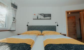 A cozy bedroom with two beds and yellow bedspreads. The room has plenty of daylight and a modern atmosphere.