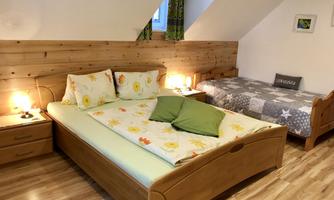 A cozy bedroom with two wooden beds. The walls are clad in wood and there are decorative cushions and night lights.
