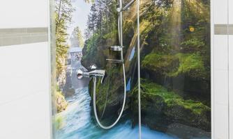 A modern shower with a beautiful wall design depicting a waterfall amidst trees. The image conveys a sense of nature and relaxation.