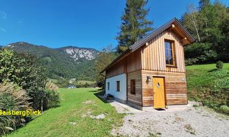A charming wooden house in a picturesque setting. In the background, mountains and green meadows can be seen.