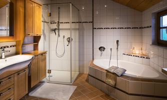 A modern bathroom with a glass shower and a cozy bathtub. The wood paneling and tiles give the room a warm atmosphere.
