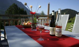 A beautifully set table on a terrace with a view of the mountains. Glasses and wines are ready for a relaxed gathering.