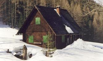 A cozy wooden house in a snowy landscape. Surrounded by trees and fresh snow.