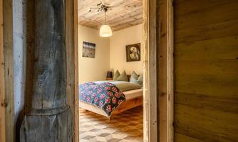 A cozy bedroom with a large bed and floral decor. The room has wooden walls and a warm, inviting atmosphere.