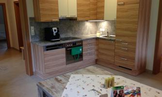 A modern kitchen with wooden cabinets and gray stone look. On the table lie decorative materials and brochures.